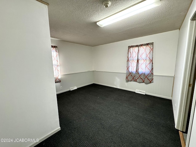 carpeted empty room featuring a textured ceiling