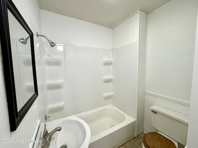 full bathroom featuring tile patterned floors, bathtub / shower combination, a textured ceiling, sink, and toilet