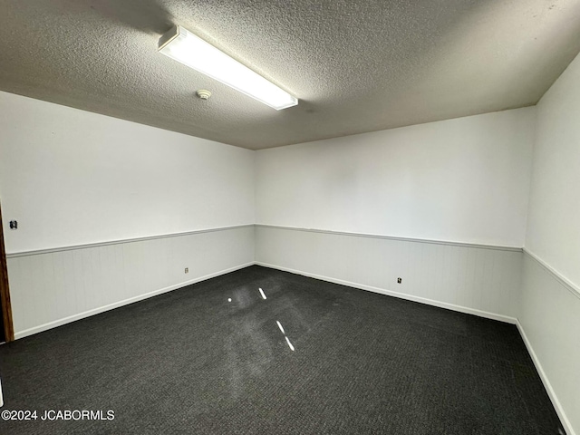 unfurnished room with dark colored carpet and a textured ceiling