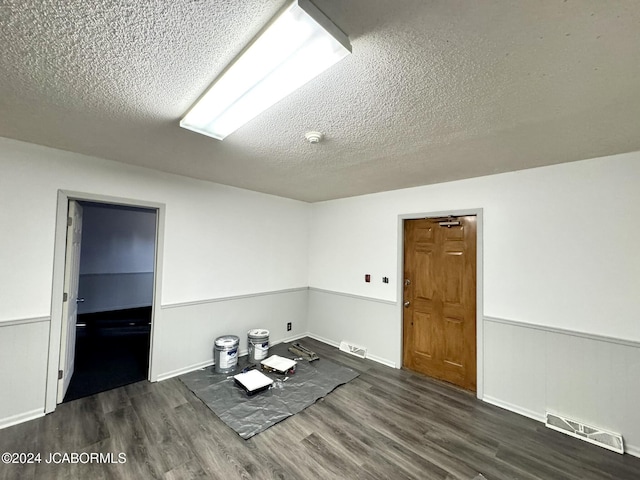 unfurnished room with dark hardwood / wood-style flooring and a textured ceiling