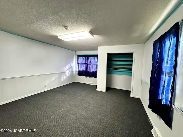 unfurnished room with dark carpet and a textured ceiling