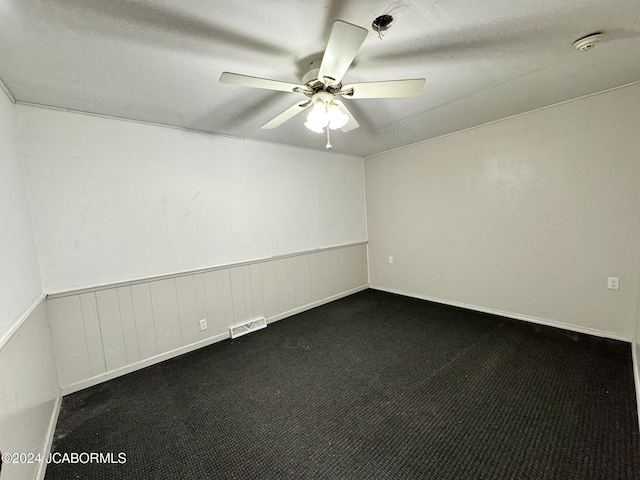 spare room with ceiling fan and dark carpet