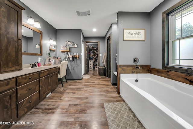 11169 Ridge Fork Dr, Holts Summit, MO 65043 - bathroom featuring vanity, a bath, a spacious closet, wood finished floors, and recessed lighting