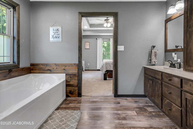 11169 Ridge Fork Dr, Holts Summit, MO 65043 - ensuite bathroom featuring vanity, a ceiling fan, a bath, wood finished floors, and a raised ceiling