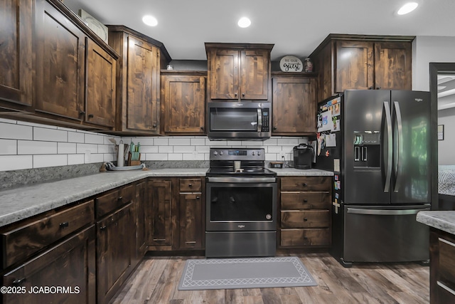 11169 Ridge Fork Dr, Holts Summit, MO 65043 - kitchen with black fridge with ice dispenser, stainless steel electric range, wood finished floors, decorative backsplash, and recessed lighting