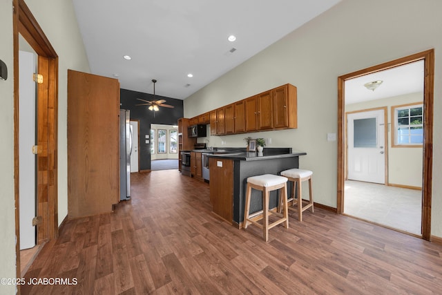 822 Center St, Fulton, MO 65251 - kitchen with dark wood-type flooring, a peninsula, plenty of natural light, brown cabinets, and recessed lighting