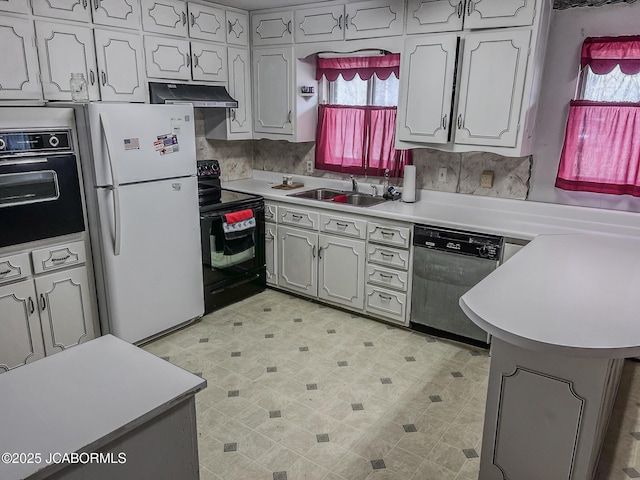 kitchen with light floors, light countertops, a sink, under cabinet range hood, and black appliances