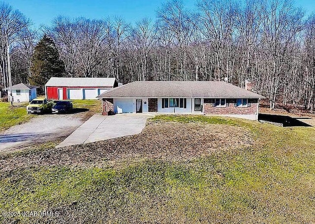 ranch-style home featuring an outbuilding, concrete driveway, and a front yard