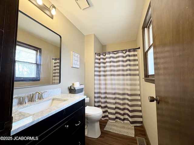 full bath featuring visible vents, a shower with shower curtain, toilet, wood finished floors, and vanity