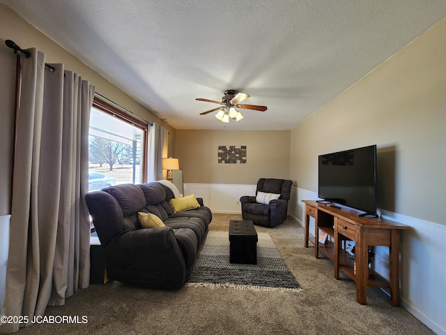 living room featuring carpet, a ceiling fan, and a textured ceiling