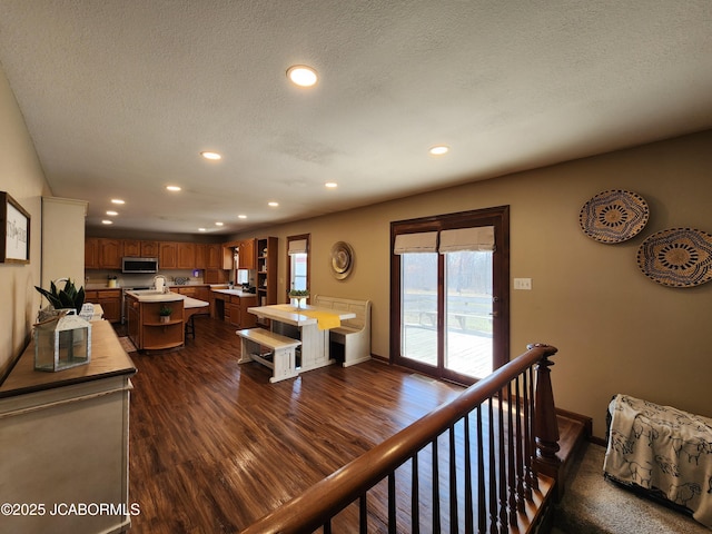 living area featuring a textured ceiling, dark wood-type flooring, and recessed lighting