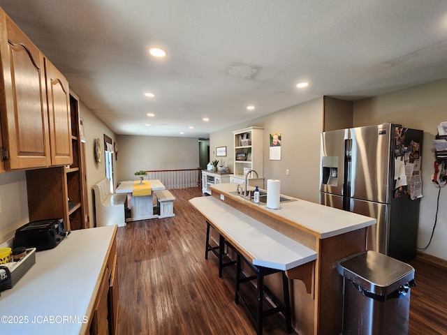 kitchen with dark wood-style floors, a kitchen island with sink, a sink, and stainless steel fridge with ice dispenser