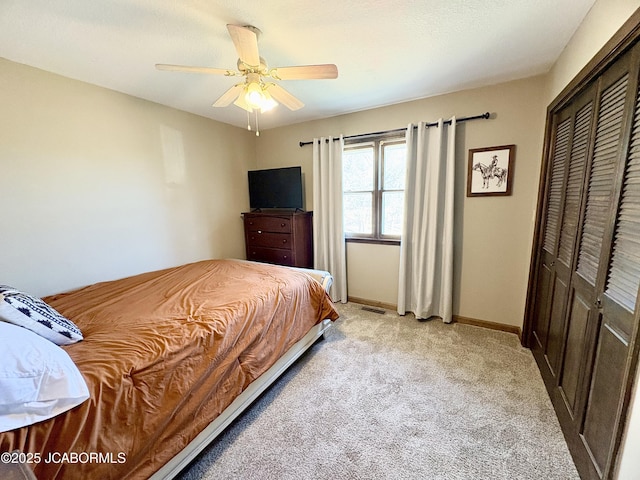 bedroom featuring a closet, visible vents, a ceiling fan, light carpet, and baseboards