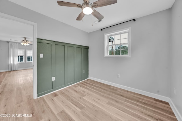 53036 Bird Haven Rd, Centertown, MO 65023 - unfurnished bedroom featuring multiple windows, light wood-style floors, and a ceiling fan