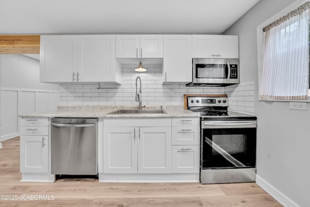 53036 Bird Haven Rd, Centertown, MO 65023 - kitchen featuring appliances with stainless steel finishes, white cabinets, decorative backsplash, light stone counters, and light wood-style flooring
