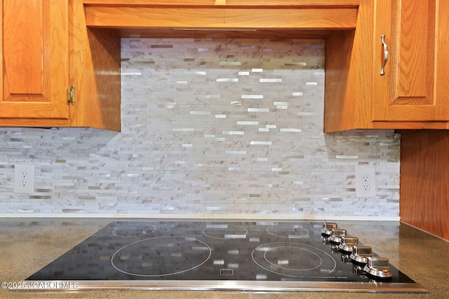 907 Primrose Ln, Jefferson City, MO 65109 - kitchen view of black electric stovetop, decorative backsplash, and brown cabinets