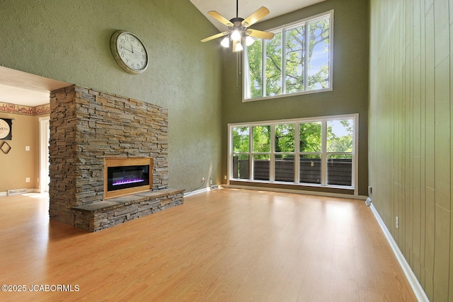 907 Primrose Ln, Jefferson City, MO 65109 - unfurnished living room with wood finished floors, a stone fireplace, a ceiling fan, and a high ceiling