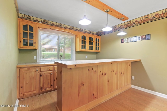 907 Primrose Ln, Jefferson City, MO 65109 - kitchen featuring light wood-type flooring, glass insert cabinets, tile counters, and pendant lighting