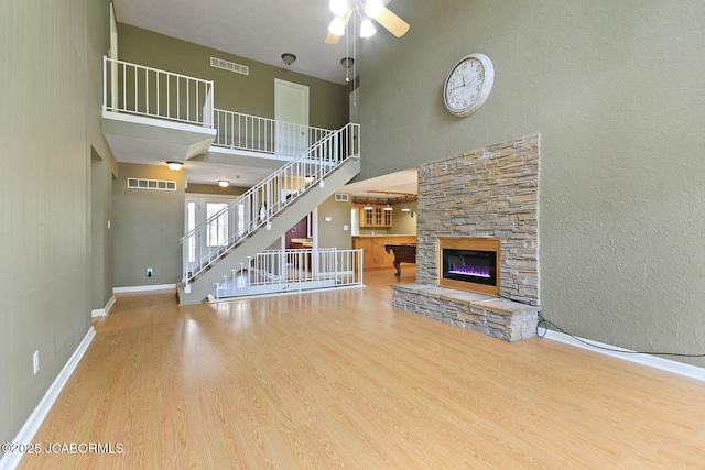 907 Primrose Ln, Jefferson City, MO 65109 - unfurnished living room featuring wood finished floors, a ceiling fan, a high ceiling, stairs, and a fireplace
