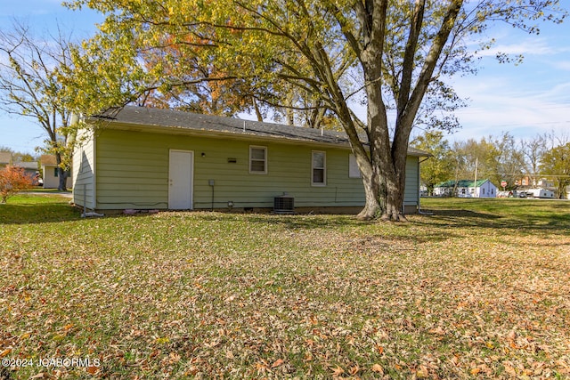 rear view of property featuring central AC unit and a yard