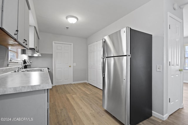 kitchen with stainless steel refrigerator, sink, and light wood-type flooring