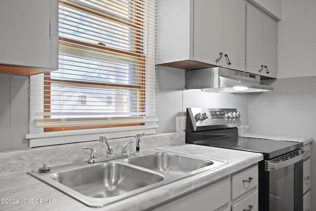 kitchen with electric stove, sink, and white cabinets