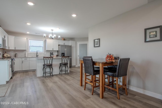 dining area with light hardwood / wood-style flooring, a notable chandelier, and sink