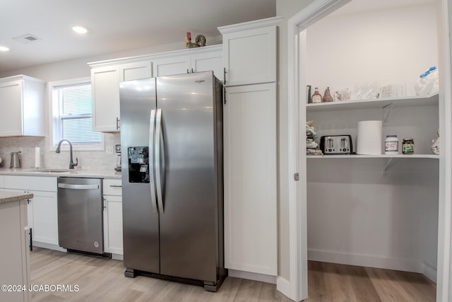 kitchen with light wood-type flooring, white cabinetry, sink, and appliances with stainless steel finishes