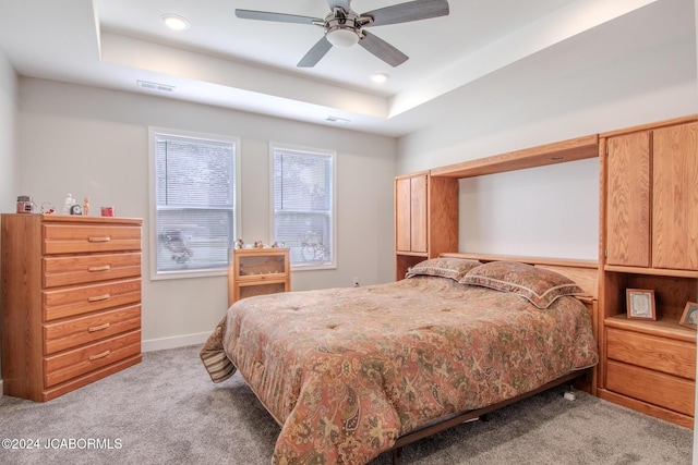 bedroom featuring light carpet, a raised ceiling, and ceiling fan