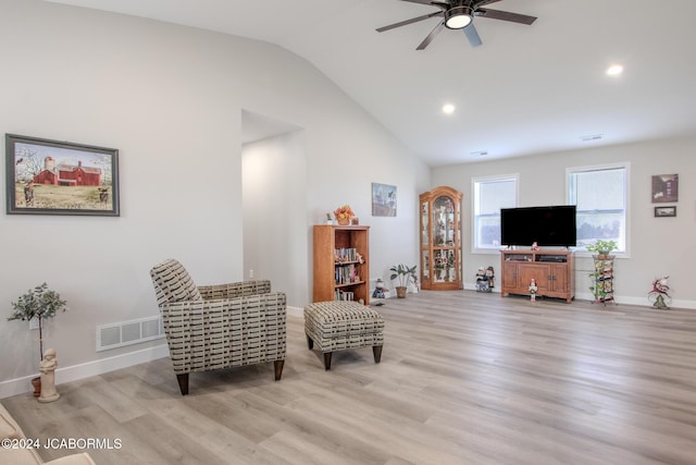 living area featuring light hardwood / wood-style floors, vaulted ceiling, and ceiling fan