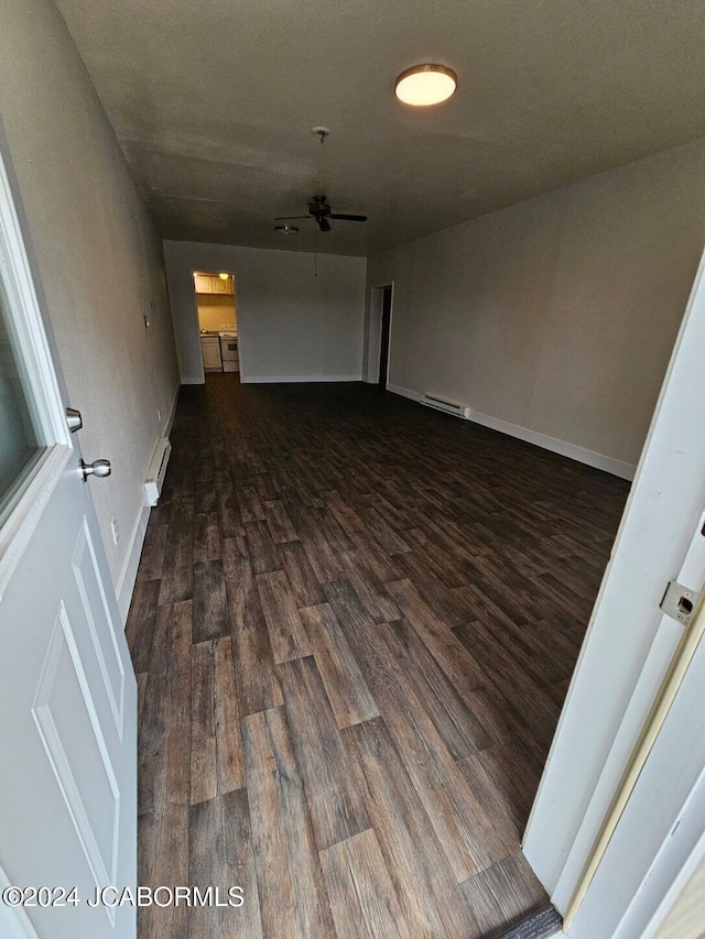 empty room featuring dark hardwood / wood-style flooring, baseboard heating, and ceiling fan