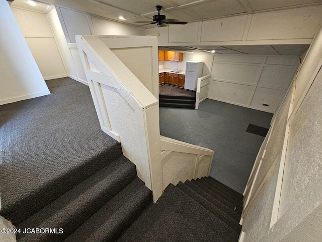 staircase featuring ceiling fan and carpet floors