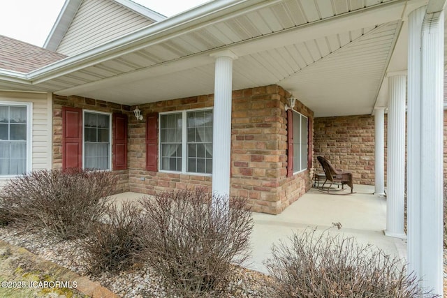 exterior space with covered porch, a shingled roof, and brick siding