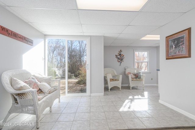 living area featuring a drop ceiling and light tile patterned flooring