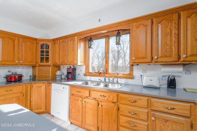 kitchen featuring light tile patterned floors, backsplash, white dishwasher, and sink