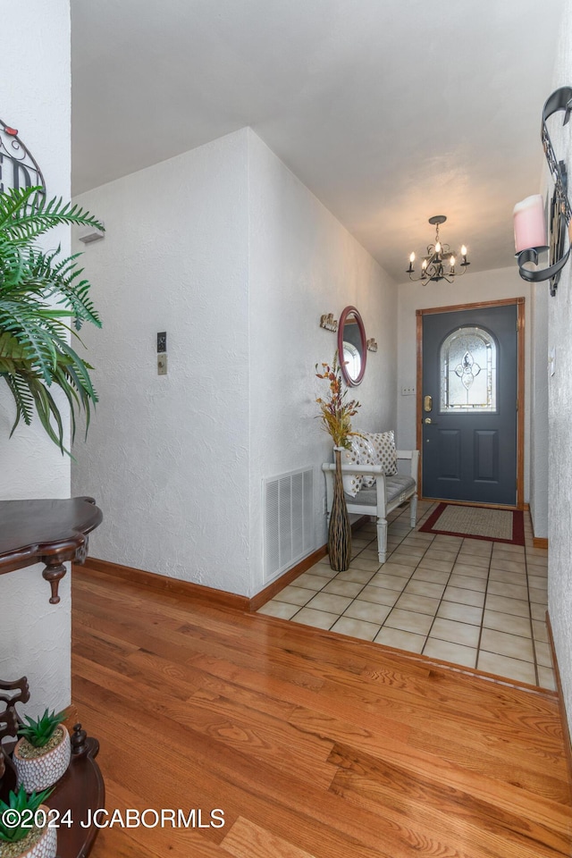 foyer featuring light wood-type flooring and a notable chandelier