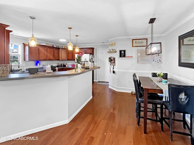 604 Mustang Dr, Ashland, MO 65010 - kitchen with ornamental molding, dark wood-type flooring, pendant lighting, a peninsula, and refrigerator