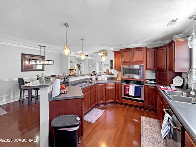 604 Mustang Dr, Ashland, MO 65010 - kitchen with appliances with stainless steel finishes, dark wood-style floors, a peninsula, ornamental molding, and decorative light fixtures