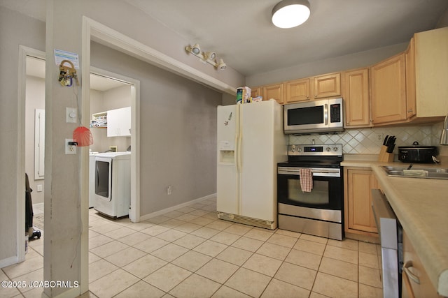 kitchen with washer / dryer, light brown cabinetry, tasteful backsplash, a sink, and stainless steel appliances