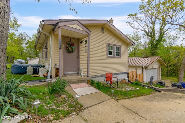 bungalow-style home with a garage, an outbuilding, and metal roof