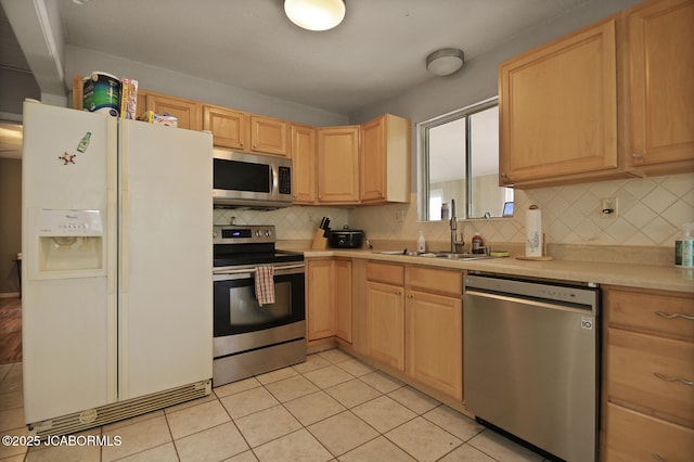 kitchen featuring light brown cabinets, light countertops, tasteful backsplash, a sink, and stainless steel appliances