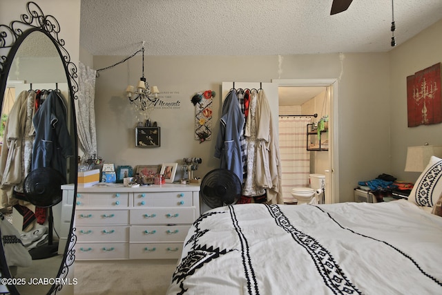 bedroom with ceiling fan, carpet, ensuite bath, and a textured ceiling