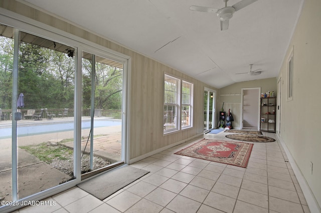 unfurnished sunroom featuring baseboards, tile patterned floors, and vaulted ceiling