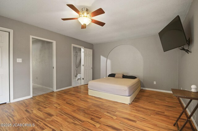 bedroom featuring connected bathroom, baseboards, ceiling fan, and wood finished floors