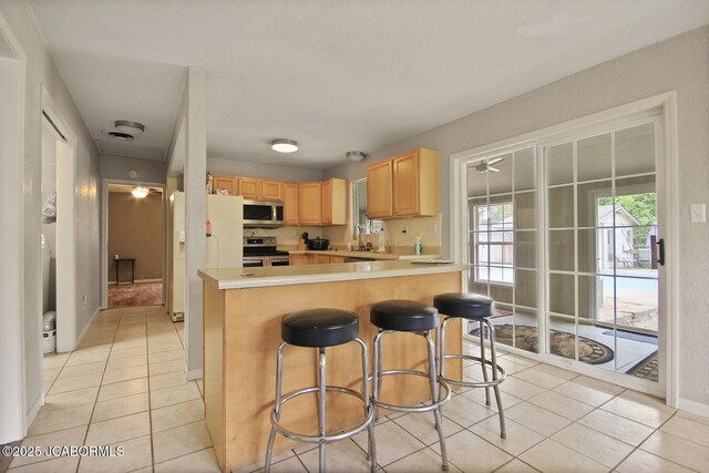 kitchen featuring light countertops, appliances with stainless steel finishes, light tile patterned floors, and light brown cabinets