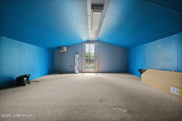 bonus room featuring carpet flooring, a textured wall, and vaulted ceiling