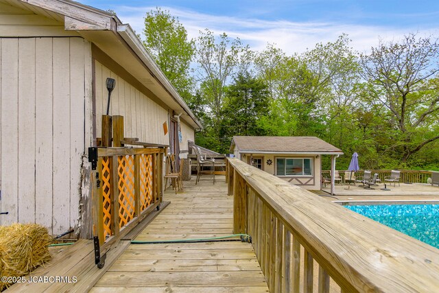 wooden terrace featuring a fenced in pool and an outdoor structure