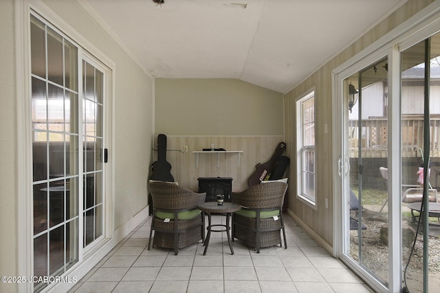 sunroom with baseboards, tile patterned flooring, a wood stove, and lofted ceiling