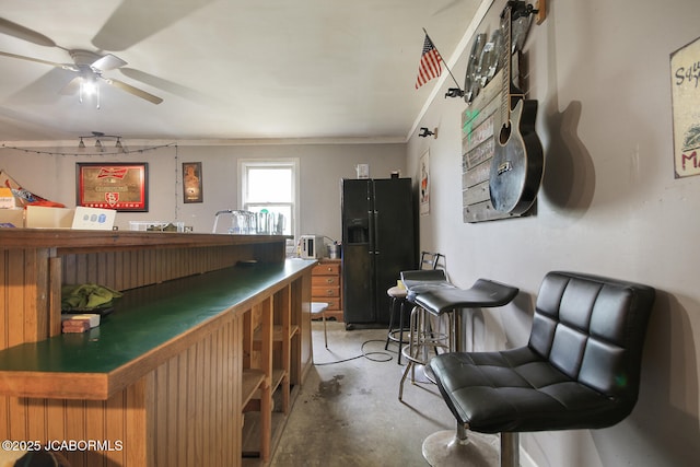 interior space with black fridge with ice dispenser, a dry bar, concrete floors, and ornamental molding