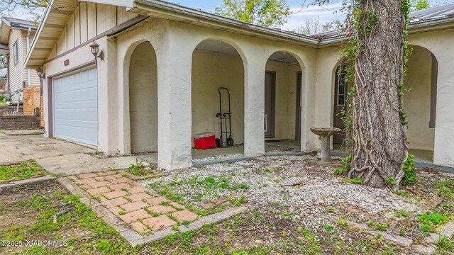 entrance to property featuring an attached garage and stucco siding